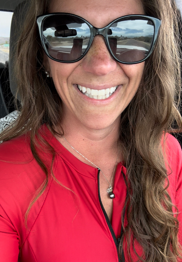 Hi From Ashley in a red rash guard, sunglasses and a big smile