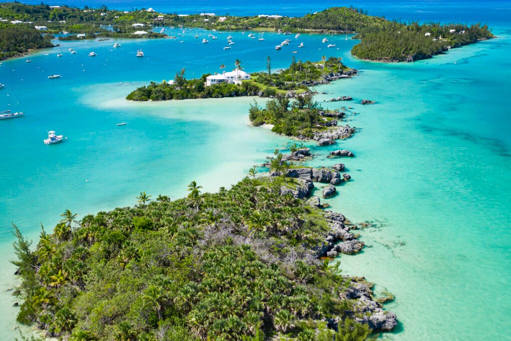 Drone image of Bermuda, bright, glowing blue and turquoise water with multiple islands full of lush green trees